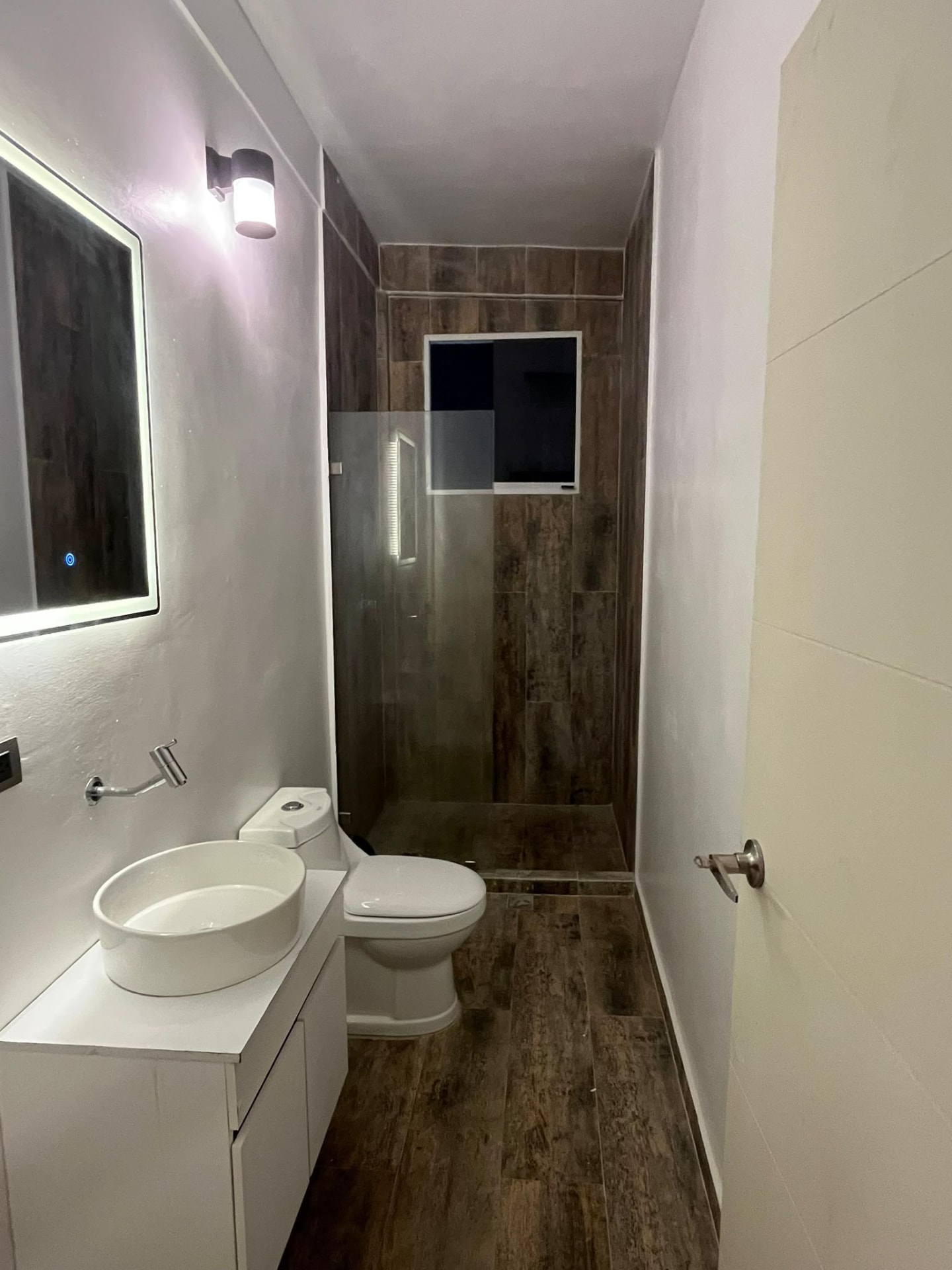 Baño con ducha y acabados en tono madera