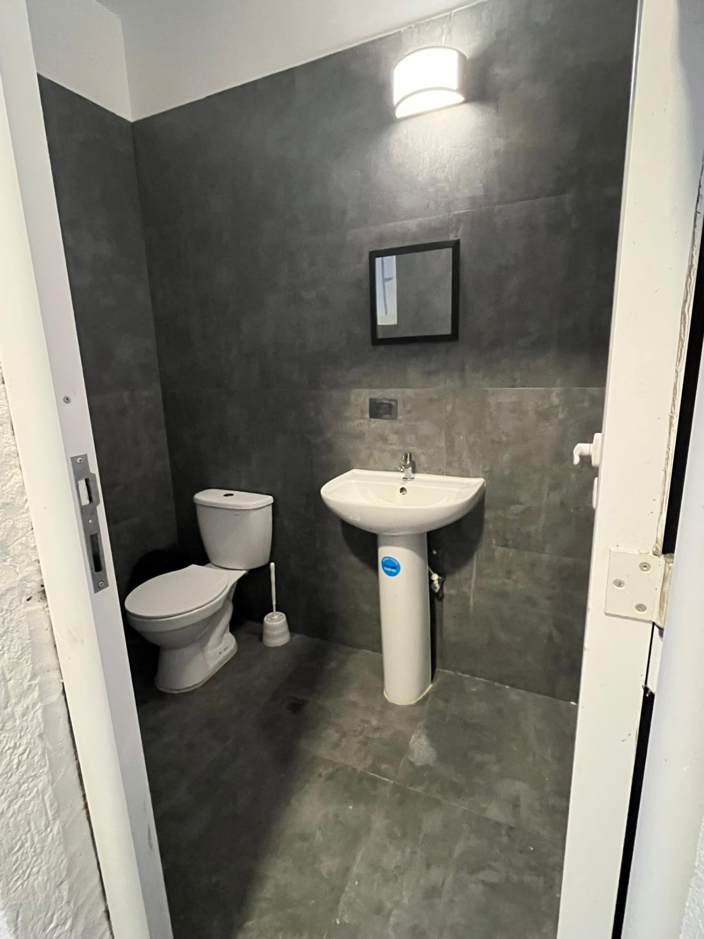 Baño auxiliar con acabados en gris